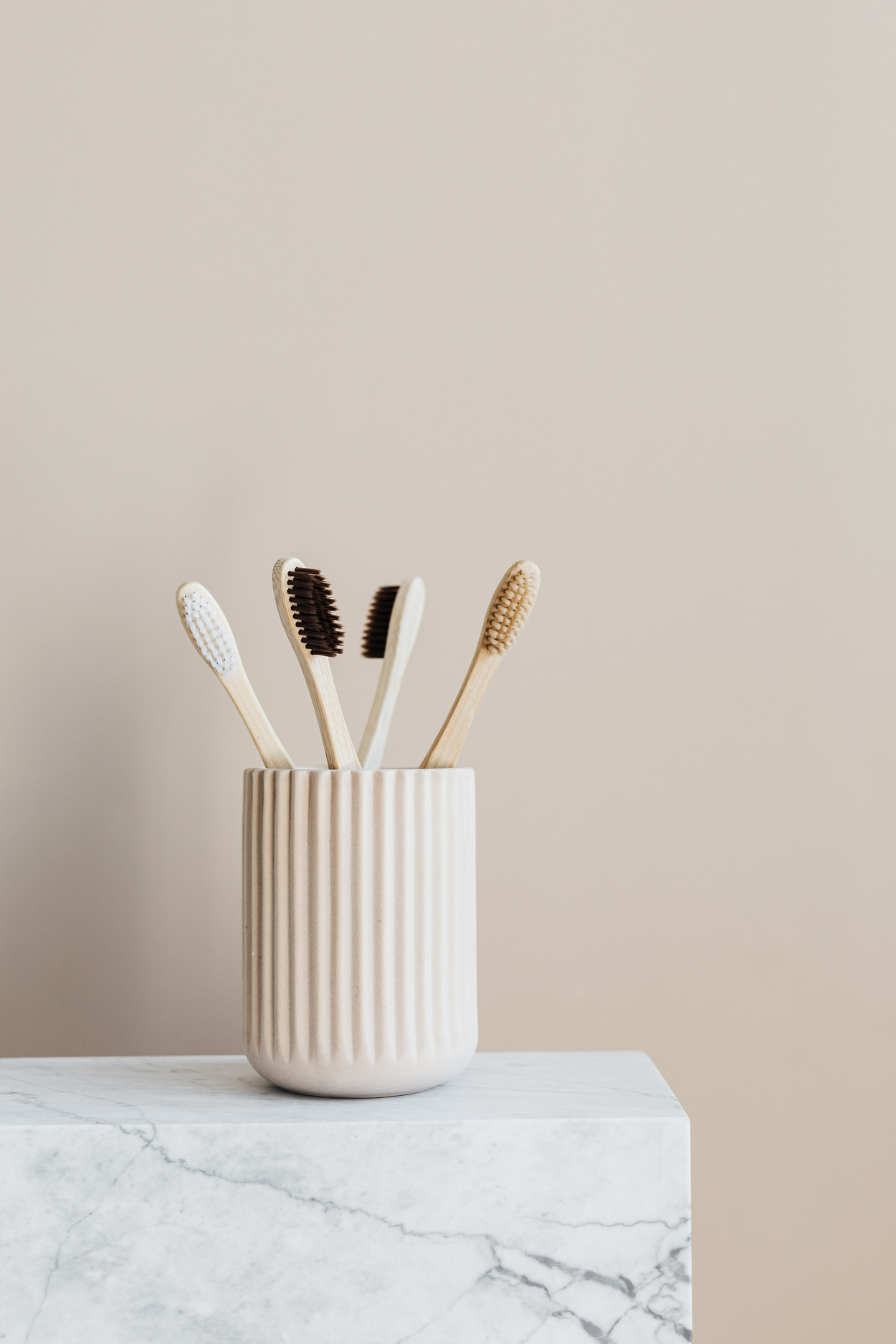 Set of natural wooden toothbrushes in white holder